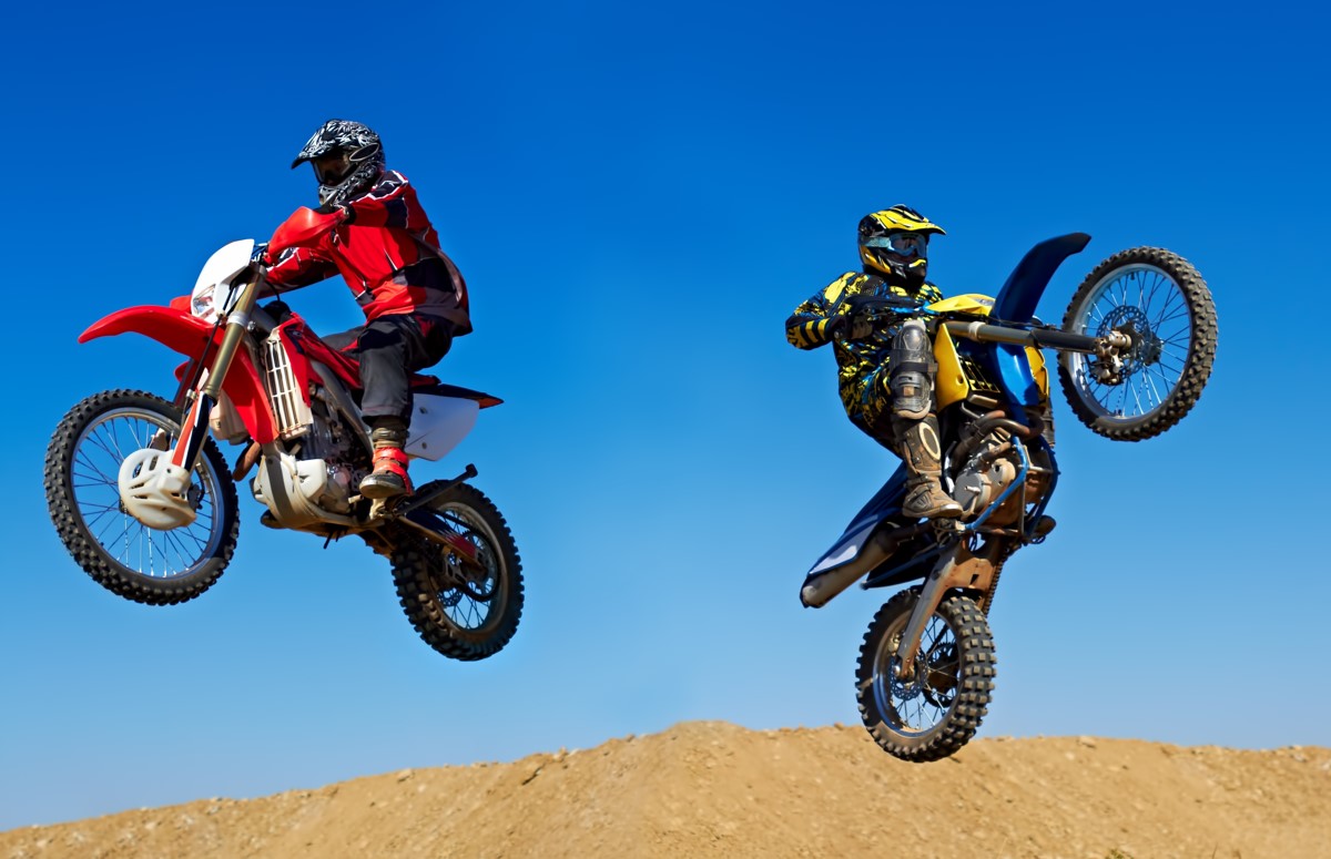 Extreme to the max. Action shot of two dirt bikers jumping in different directions.