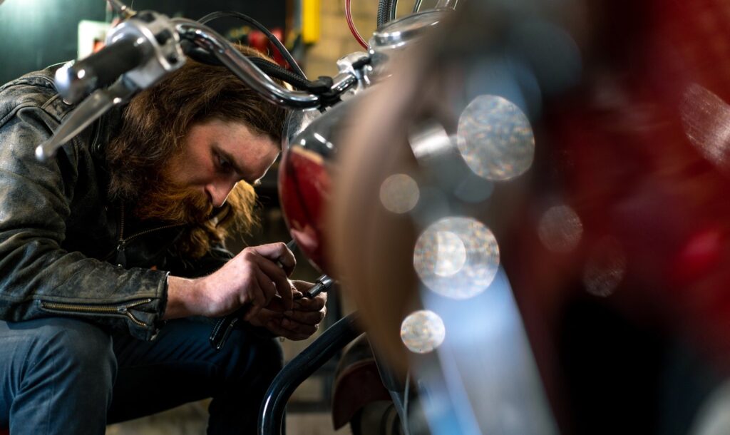 authentic motorcycle workshop Garage redhead bearded biker mechanic on repairing motorcycle